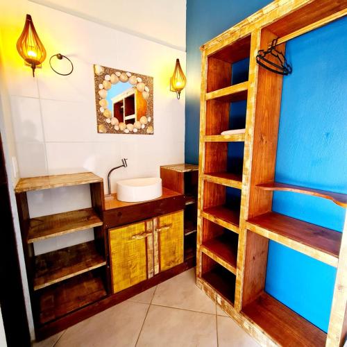 a bathroom with wooden shelves and a sink at Pousada Doce Mar in Guarda do Embaú