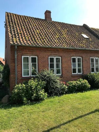 una casa de ladrillo rojo con arbustos delante de ella en Vidunderligt hus på smukke Nyord en Stege