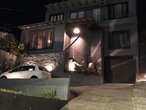 ein Auto, das nachts vor einem Haus parkt in der Unterkunft CASA CONCEITO - studio panoramico, suites e quartos in São José