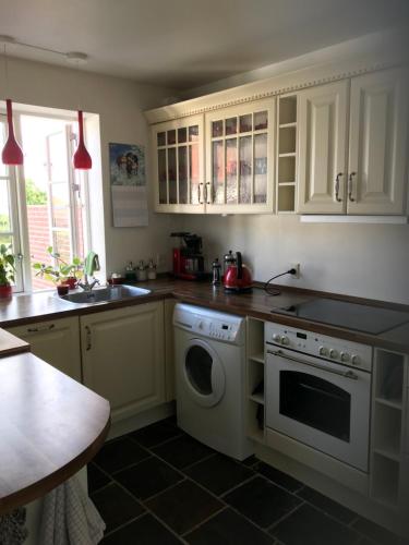 a kitchen with white cabinets and a dishwasher at Vidunderligt hus på smukke Nyord in Stege