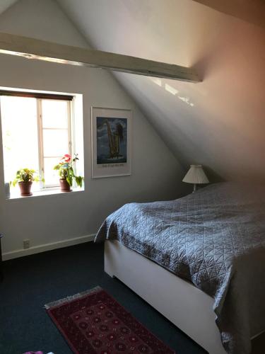 a attic bedroom with a bed and two windows at Vidunderligt hus på smukke Nyord in Stege