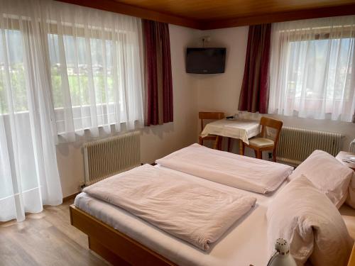 a bedroom with two beds and a table and windows at Haus Gröblacher in Mayrhofen