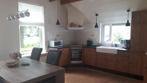 a kitchen with a wooden table and a kitchen with a sink at Gastenverblijf Boerengeluk in Gersloot