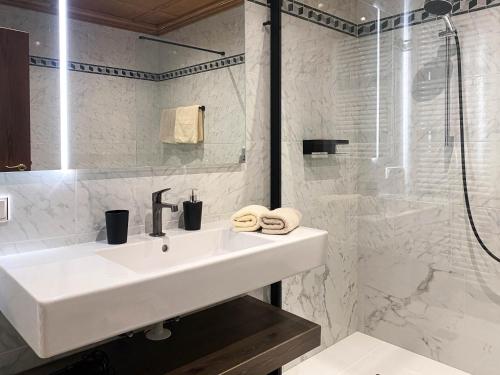 Un baño blanco con lavabo y ducha. en Apartments Ciasa Colz, en La Villa