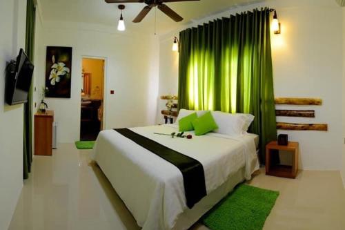 a bedroom with a large bed with a green curtain at Rangali Etos Guraidhoo in Guraidhoo