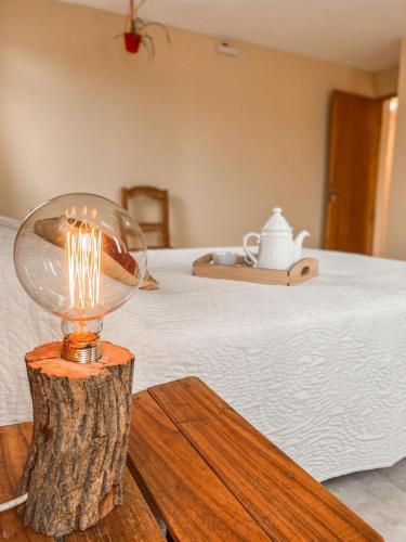 une lampe sur une table en bois à côté d'un lit dans l'établissement Diente de León, à Trevelín