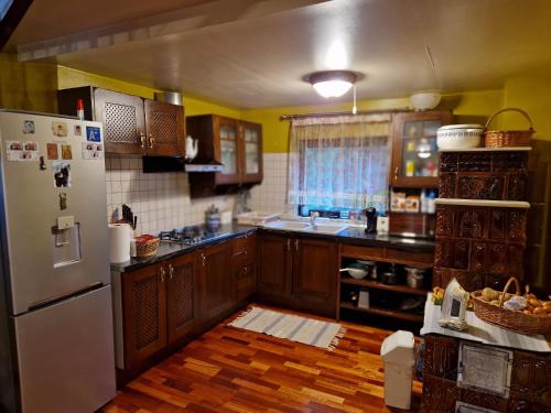 a kitchen with wooden cabinets and a white refrigerator at Cabana Casuta de Ciocolata in Teşila