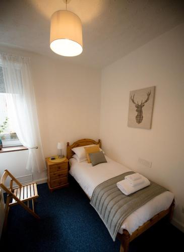 a small bedroom with a bed and a lamp at Armadale Apartment in Fort William