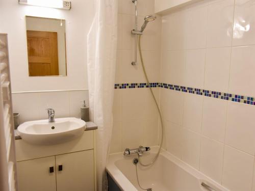 a white bathroom with a sink and a shower at Red Gable Cottage in Shap