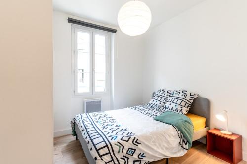 a white bedroom with a bed and a window at Appartement Terreau in Manosque