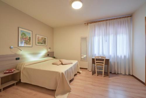 a bedroom with a bed and a table and a window at Hotel da Romagnolo in Noventa Vicentina