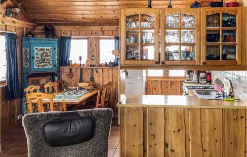 a kitchen with wooden cabinets and a table with a chair at Nice Home In Hovden I Setesdalen in Hovden