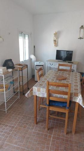 a living room with a table and chairs and a tv at Casa da Oliveira in São Marcos do Campo