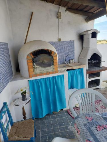 a kitchen with an oven with a table and a chair at Casa da Oliveira in São Marcos do Campo