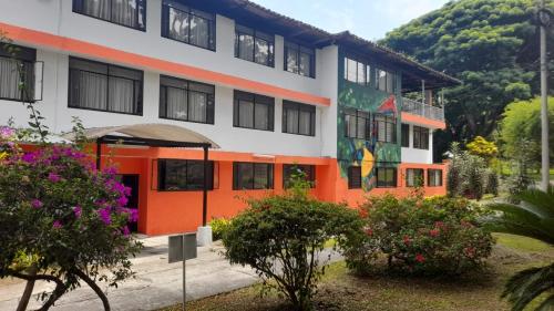 an orange and white building with flowers in front of it at Imca Hotel in Buga