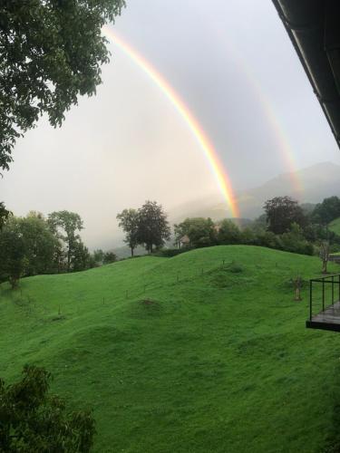 a rainbow over a green field with a hill at Hotel Cafe Seeblick in Filzbach