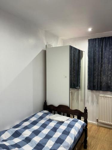 um quarto com uma cama com um cobertor xadrez azul e branco em Comfortable single bedroom with free on site parking em Kingston upon Thames