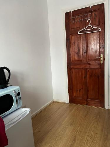 um quarto com uma porta de madeira e um micro-ondas em Comfortable single bedroom with free on site parking em Kingston upon Thames