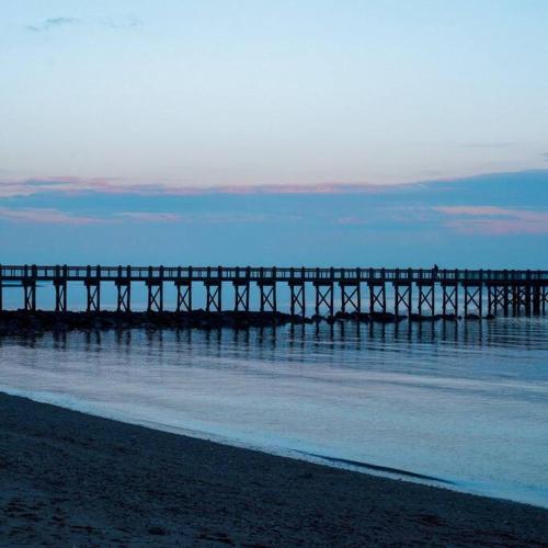 a pier over the water with a person on it at Milford Entire House near Walnut Beach in Milford