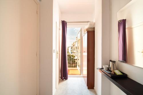pasillo con puerta a un balcón con cortinas moradas en Hostal Bonanza, en Sitges