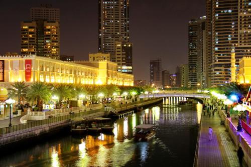 a river in a city at night with buildings at Sharjah Rose Tower in Sharjah