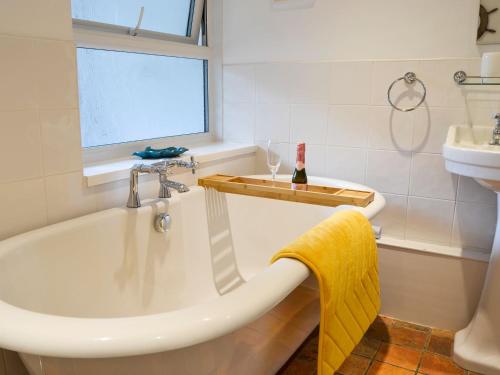 Tree Tops Cottage في Mundford: حمام مع حوض ومغسلة ونافذة