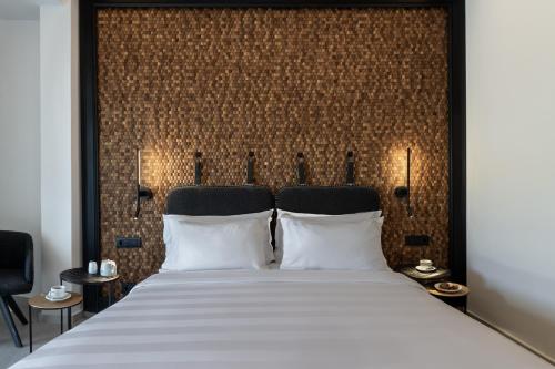 a bedroom with a large white bed with a wall at Petinos Hotel in Platis Yialos Mykonos