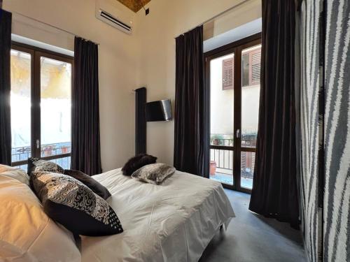 una camera da letto con letto, cuscini e finestre di Sant'Andrea - Luxury Rooms in Vucciria a Palermo