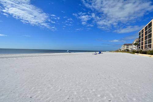 a white sandy beach with a building and the ocean at Villa Madeira 506 - Premier in St Pete Beach