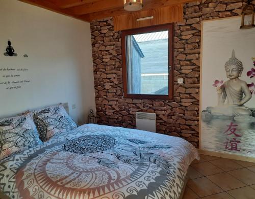 een slaapkamer met een groot bed en een stenen muur bij Le Canari in Huisnes-sur-Mer