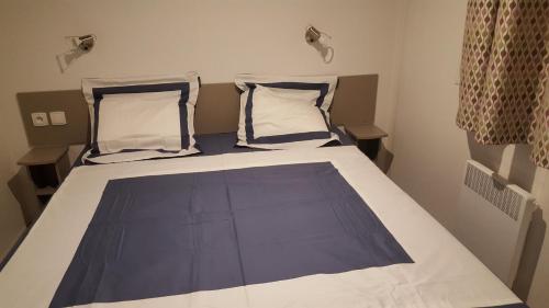 a bedroom with a bed with blue and white sheets and pillows at Agréable Mobilhome 6 - 8 places in Saint-Brevin-les-Pins