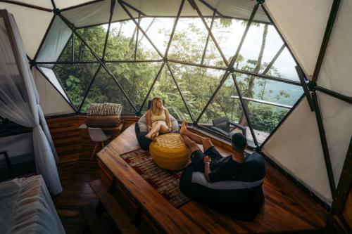 Un uomo e una donna seduti in una stanza in una tenda a cupola di Trekker Glamping a Minca