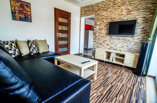 salon z czarną skórzaną kanapą i telewizorem w obiekcie AM-Residence No. 19 w Wiedniu