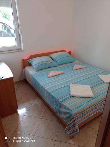 a bedroom with a bed with blue sheets and a window at House Vida Goraleks in Baška Voda