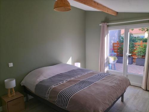 a bedroom with a bed and a large window at agréable maison de vacances en Charente-Maritime in Arvert