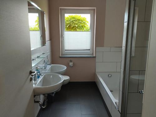 baño con 2 lavabos, bañera y ventana en RK Apartments Birnbaum en Gerhardshofen
