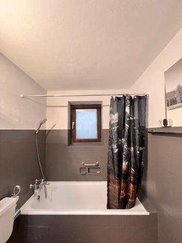 a bathroom with a tub and a shower curtain at Alpine Retreat in Garmisch-Partenkirchen