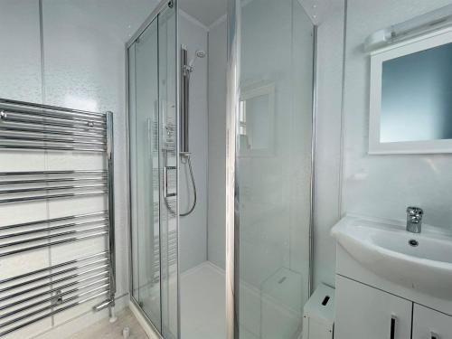 baño blanco con ducha y lavamanos en Harbour Street en Portmahomack