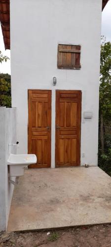 ein Haus mit zwei Holztüren und einem WC in der Unterkunft Cantinho HAKUNA MATATA-Vale do Capão a 5 min da Vila in Vale do Capao