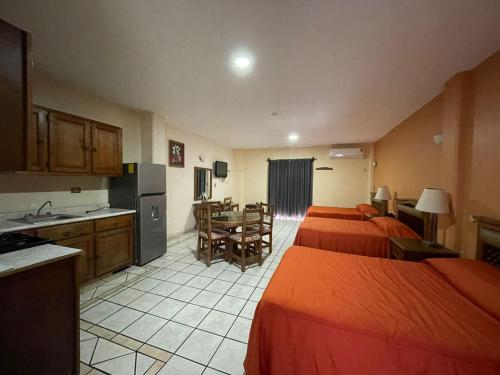 a hotel room with four beds and a kitchen at Hotel Las Fuentes in Los Mochis