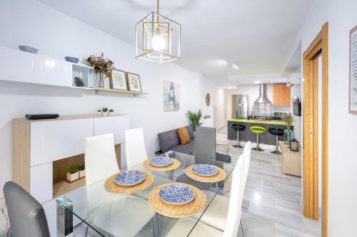 comedor y cocina con mesa de cristal y sillas en Grace Apartments - 3 bedroom City Centre, en Granada