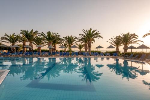 ein großer Pool mit Palmen und Sonnenschirmen in der Unterkunft Mediterraneo Hotel in Hersonissos