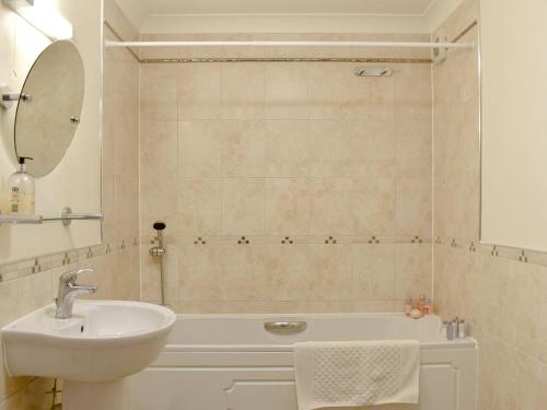 a bathroom with a sink and a tub and a mirror at Seaview Apartment - 21 Spinnakers in Newquay