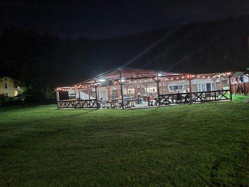 a building with picnic tables in a field at night at Pensiunea Mayumi Moneasa in Moneasa