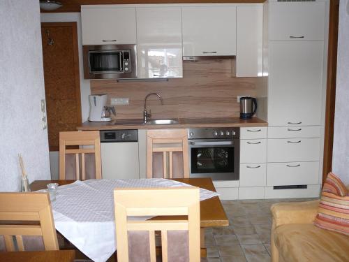 una cocina con armarios blancos y una mesa en una habitación en Ferienhäuschen Kathrein, en Ehenbichl