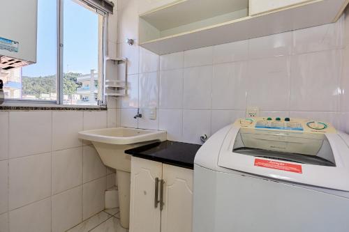 La salle de bains blanche est pourvue d'un lavabo et d'un lave-linge. dans l'établissement 1040 - Departamento 2 quartos na Rua Pirajica . 200 m da Praia Bombinhas Centro, à Bombinhas