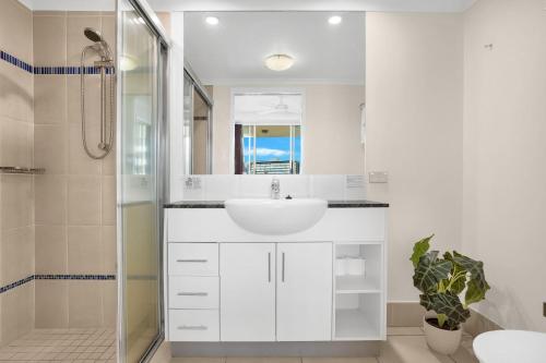 a white bathroom with a sink and a shower at City Quays Accommodation in Cairns