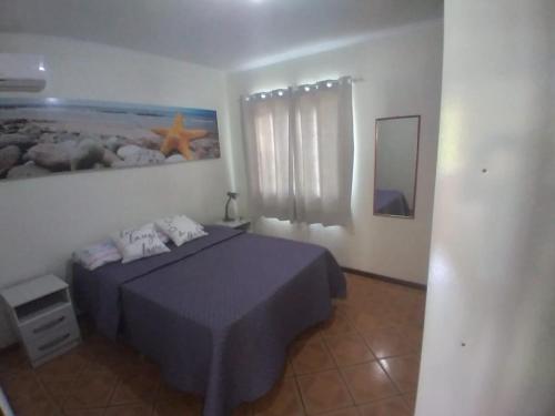 1 dormitorio con 1 cama y una pintura en la pared en residencial pilati en Bombinhas