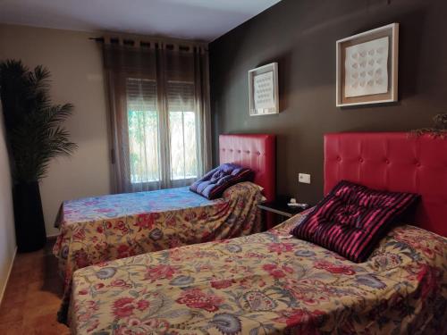 duas camas num quarto com cabeceiras vermelhas em Precioso apartamento con piscina comunitaria privada y patio exterior em Ayamonte