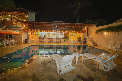 a swimming pool with two chairs and a house at Hotel Camburi Praia in Camburi